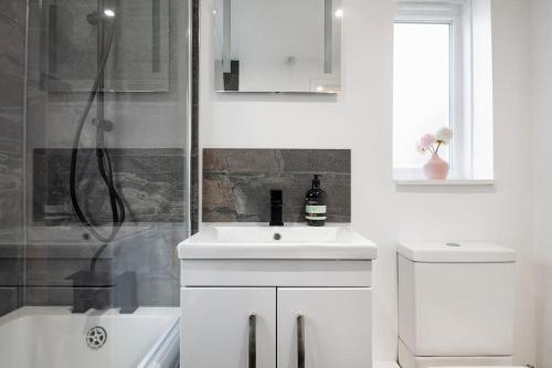 a white bathroom with a sink and a shower at Newly Renovated 2 Bed Cottage - call for discount in Windsor