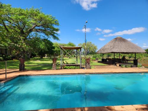 a swimming pool with a picnic table and a gazebo at River Cottage Lodge in Malelane