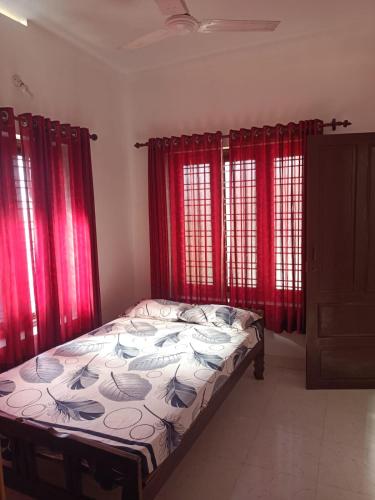 a bedroom with red curtains and a bed in a room at Beach Villa Kovalam in Kovalam