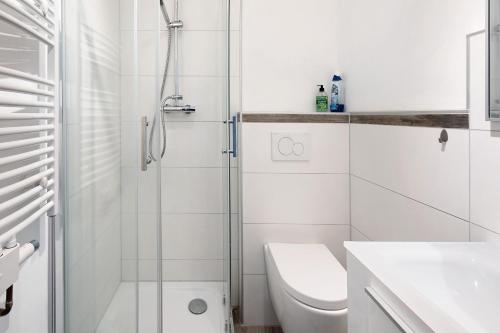 La salle de bains blanche est pourvue d'une douche et de toilettes. dans l'établissement Vogelsberger Bett 5 die 2 links, à Alsfeld