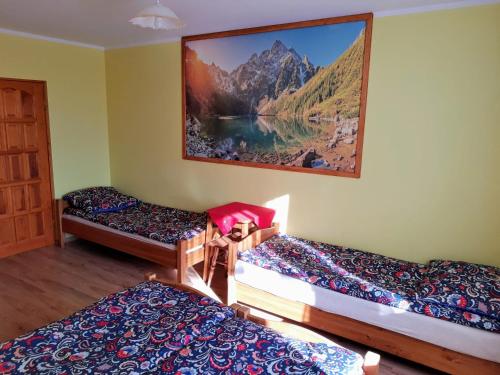 a room with three beds and a painting on the wall at Willa Wyrostek in Bańska Wyżna