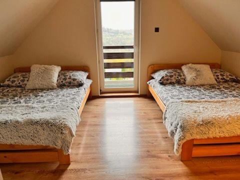 two beds in a room with a large window at Solina domki-„Solińskie wzgórze” in Solina