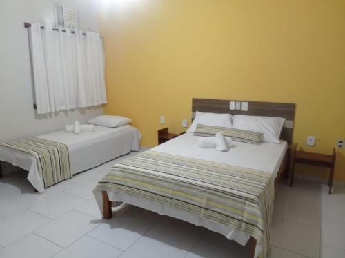 two beds in a room with yellow walls at Hotel Mata Atlântica in Corumbau