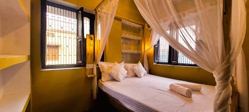 a bedroom with a canopy bed with two windows at ILIKA STAYS (DASHASHWAMEDH GHAT) in Varanasi