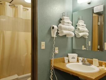 a bathroom with a sink and a mirror and towels at Sunset Inn & Suites in Lincoln