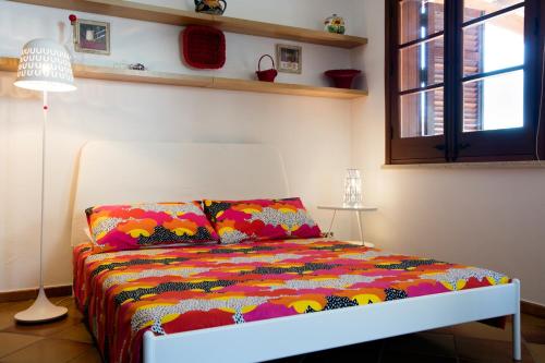 カステッルッツォにあるDependance del Poggioのカラフルな掛け布団付きのベッド1台
