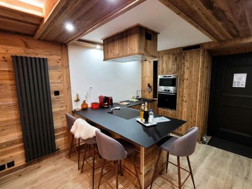 a kitchen with a black counter top and wooden walls at LES ARCS Appartement Prestige Ski In Ski Out in Bourg-Saint-Maurice