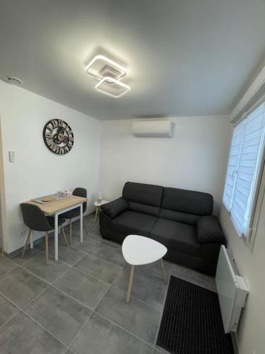ein Wohnzimmer mit einem schwarzen Sofa und einem Tisch in der Unterkunft La maisonnette Saint-quentinoise in Saint-Quentin