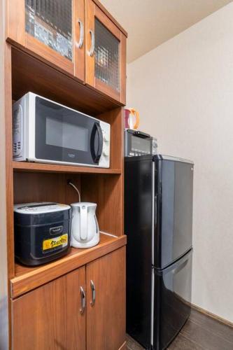 a kitchen with a black refrigerator and a microwave at Private reservation near KIX "Wakeikan" in Izumi-Sano