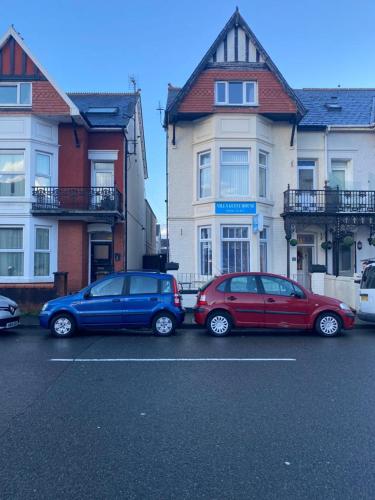 three cars parked in a parking lot in front of houses at Villa Guest House in Porthcawl