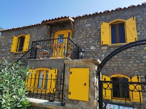 ein Gebäude mit gelben Türen und einem Balkon in der Unterkunft Ilios Guest House in Gokceada Town