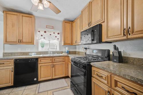 a kitchen with wooden cabinets and a black stove top oven at Palm Tree Paradise in Bradenton