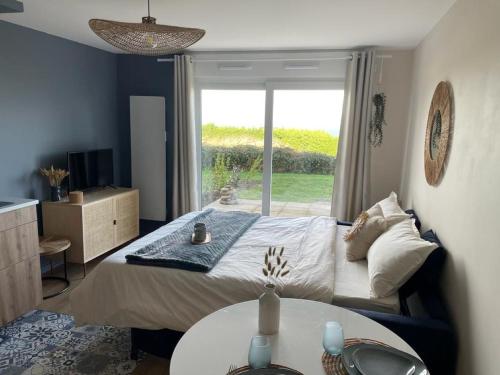 1 dormitorio con cama, mesa y ventana en Bienvenue au studio l'Escale bleue !, en Saint-Cast-le-Guildo