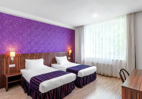 ein Hotelzimmer mit 2 Betten und einer lila Wand in der Unterkunft Rija VEF Hotel with FREE Parking in Riga