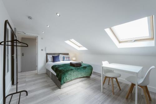 - une chambre blanche avec un lit et un bureau dans l'établissement Fulham Guest Studios 268, à Londres