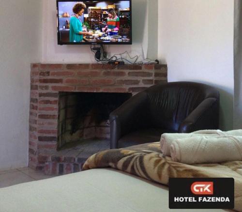 a living room with a couch and a tv above a fireplace at hotel fazenda ctk in Santa Cruz do Sul