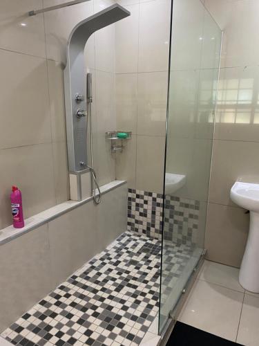 a bathroom with a shower with a checkered floor at M D J Hayfields Guest House in Pietermaritzburg