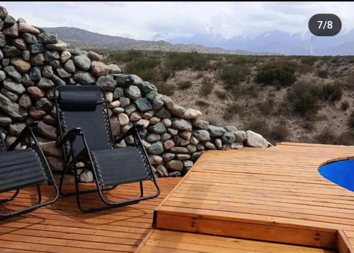 two chairs sitting on a wooden deck with a rock wall at Revolucionarte.Potrerillos in Potrerillos