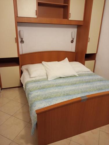 un letto con testiera in legno in una stanza di Apartmani Seršić a Baška