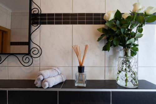 a bathroom counter with towels and a vase of flowers at City Apart Hannover in Hannover
