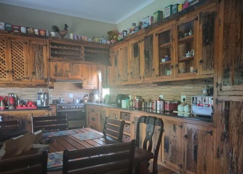 eine Küche mit Holzschränken sowie einem Tisch und Stühlen in der Unterkunft Big Boma Guest House in Lydenburg
