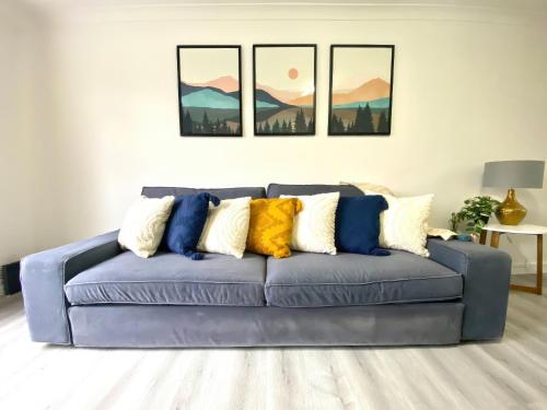 a blue couch in a living room with three paintings at Home in Farnborough with Free Parking, Wifi & Netflix in Farnborough
