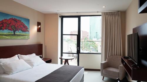 um quarto de hotel com uma cama e uma cadeira e uma janela em Chairu Eco Hotel em Santa Cruz de la Sierra