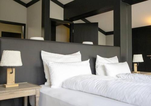 a bedroom with a large white bed with two lamps at Lauchernalp Resort Residences in Wiler