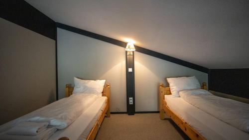 two beds in a room with a light on the wall at Lauchernalp Resort Residences in Wiler
