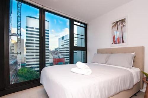 a white bed in a room with a large window at Stunning 2BR Apt nr Yarra City view Free parking in Melbourne