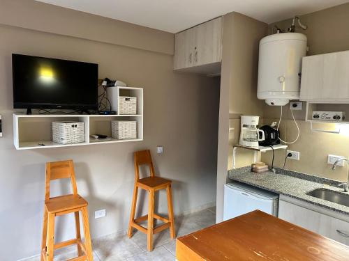 cocina con 2 sillas, mesa y TV en RETAMA en San Carlos de Bariloche