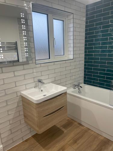 a bathroom with a sink and a tub and a mirror at Furzy House in Pembrokeshire
