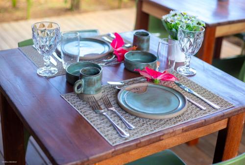 a wooden table with plates and utensils on it at Bella Rosa Noronha in Fernando de Noronha