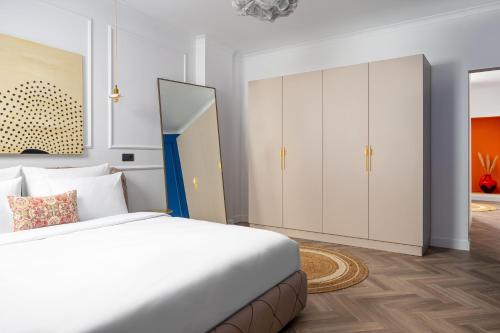 a white bedroom with a bed and a cabinet at Siesta Boutique Smart Suites in Cluj-Napoca