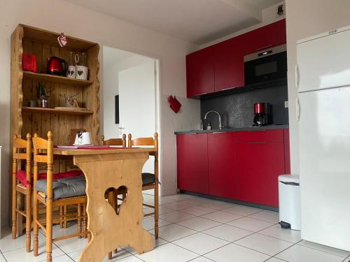 une cuisine avec une table en bois et des placards rouges dans l'établissement Appartement sur les hauteurs de Gérardmer, à Gérardmer