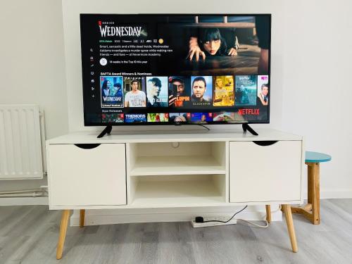 a tv on top of a white entertainment center at Home in Farnborough with Free Parking, Wifi & Netflix in Farnborough