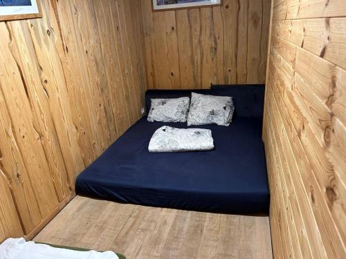 Habitación pequeña con cama azul en una pared de madera. en Pirtis link Moletu, en Vilna