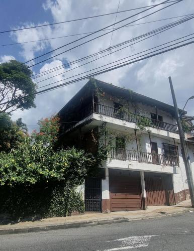 un edificio con balcón en el lateral de una calle en Casa Jardín Macondo en Medellín