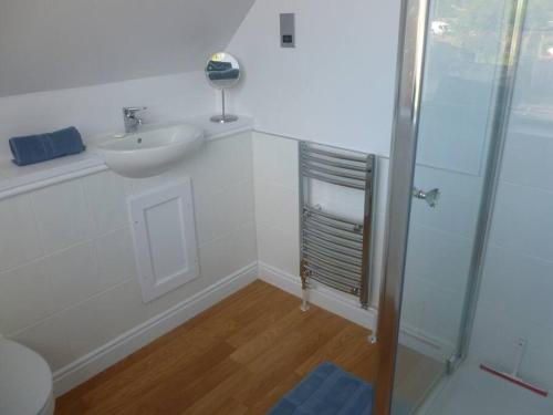 a white bathroom with a sink and a shower at The Bothy, Nethy Bridge in Nethy Bridge