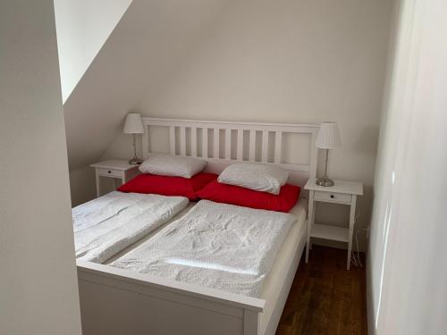 a white bed with two red pillows on it at Mitte Apartments in Brno