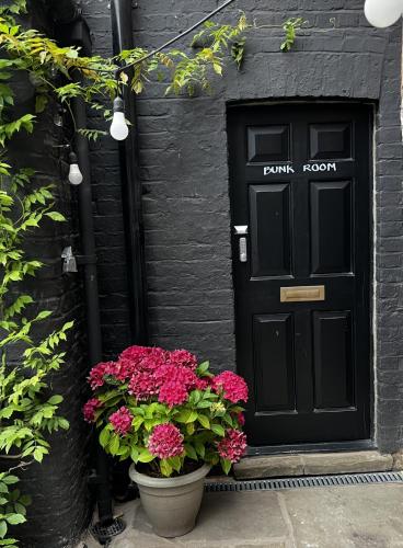 uma porta preta com flores em frente a uma casa em BOHOSTEL em Macclesfield