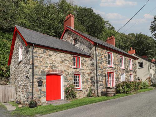 an old stone house with a red door at Sycamore Vestry in Fishguard