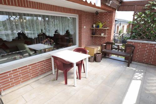 eine Terrasse mit einem Tisch, Stühlen und einem Fenster in der Unterkunft Ferienhaus Residenz Wismar - ABC430 in Wismar