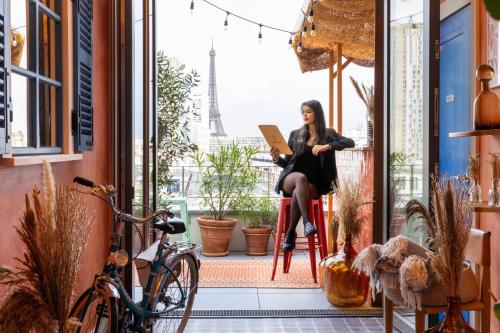 Eine Frau, die auf einem Stuhl in einem Raum mit dem Eiffelturm sitzt. in der Unterkunft Quinzerie hôtel in Paris