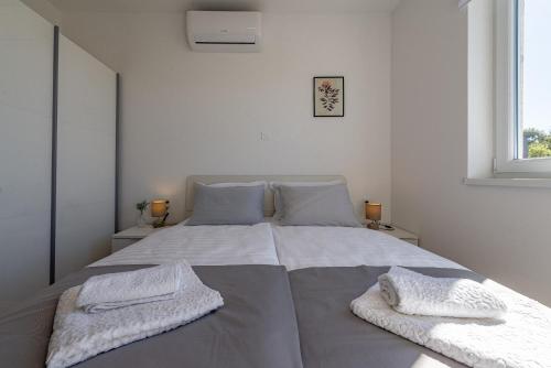 a white bedroom with a large bed with two pillows at Dolphin view with a pool by the beach in Mandre