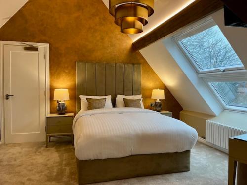 a bedroom with a large bed and two windows at Castle Hotel & Apartments in Lincoln