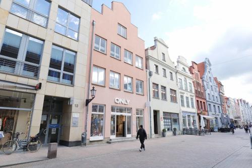 a person walking down a city street with buildings at Fewo Am Rathaus - ABC351 in Wismar