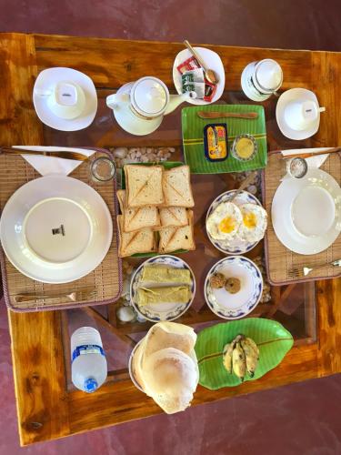 a table with plates of food and bread on it at River Cottage Safari in Udawalawe