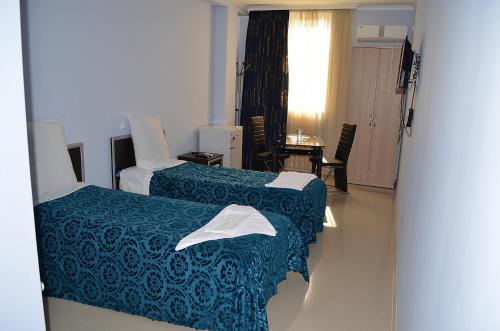 a hotel room with two beds and a table at Hotel Okriba in Kutaisi