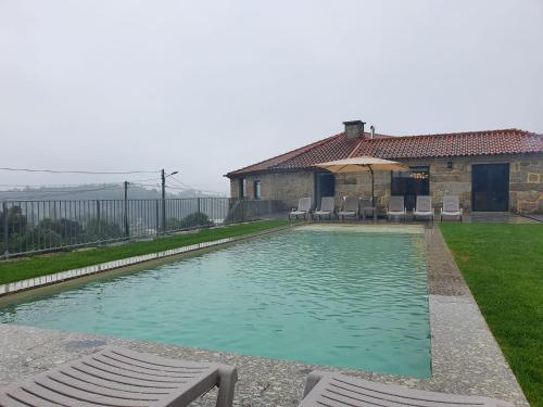 una piscina con sedie e una casa di Botica House a Póvoa de Lanhoso